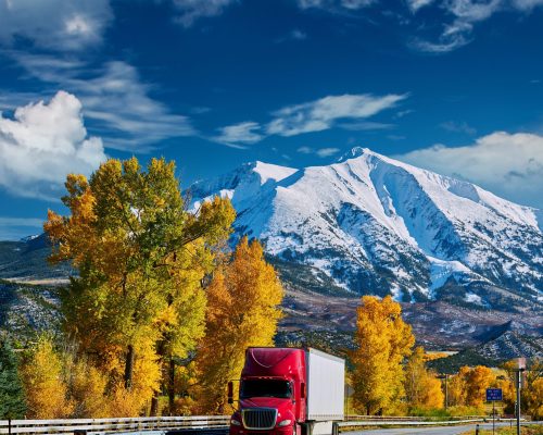 Red truck on highway in Colorado at autumn, USA. Mount Sopris landscape.