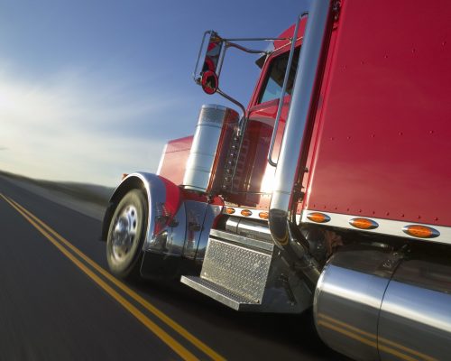 Side view of a Kenworth W900 Class 8 tuck moving on the highway.